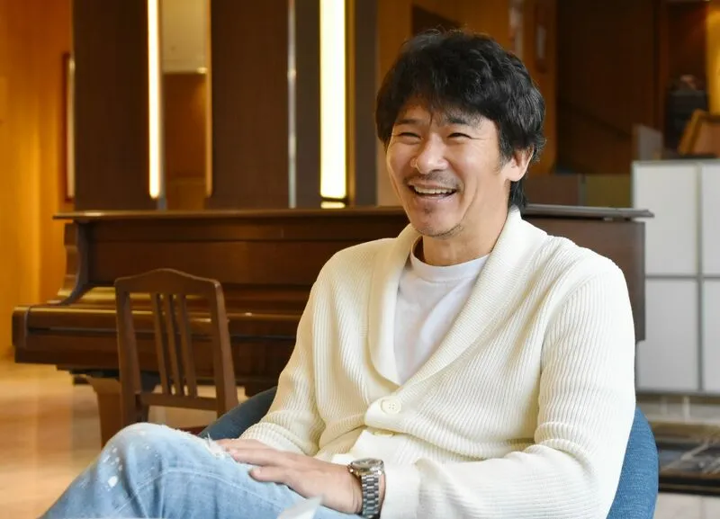 ピアノの前に座り、笑顔で話す伊原剛志さん